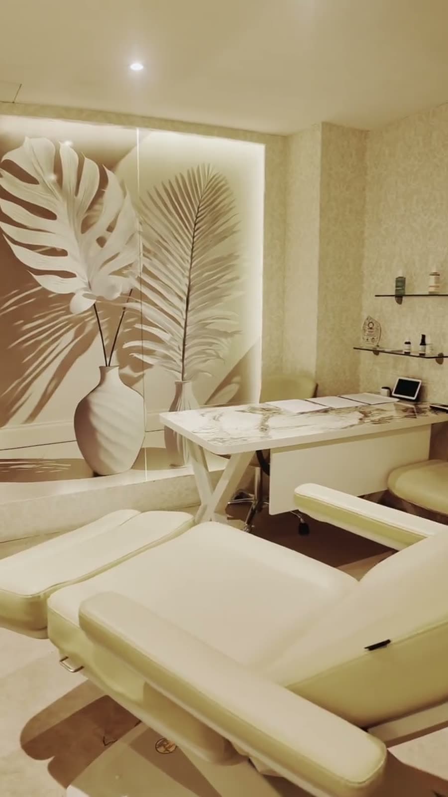 A treatment room with a backlit leaf relief and a cream chair